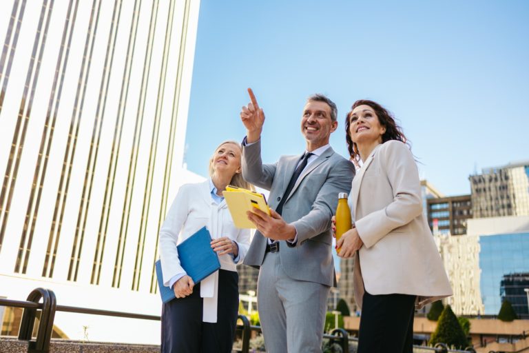Businesspeople discussing real estate investment pointing at new building